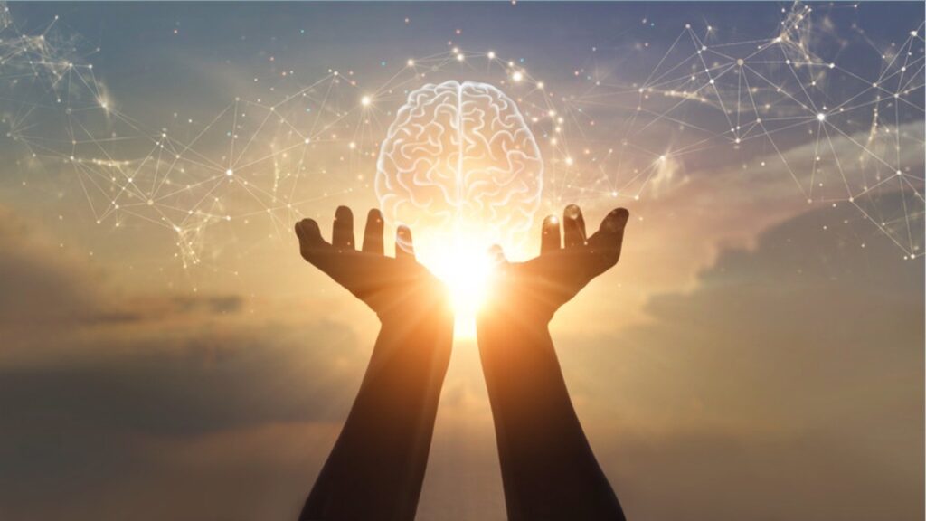 Image of hands holding a stylised brain in front of the sun